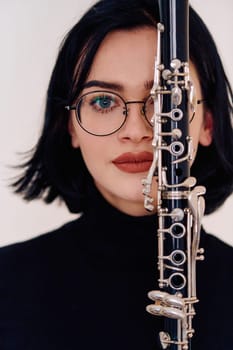 A talented brunette musician showcases her artistry as she gracefully holds and plays the clarinet against a pristine white background