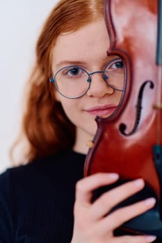 A stunning redhead musician exudes elegance as she poses with her violin, embodying both grace and musical prowess.