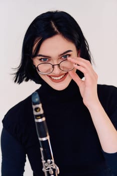 A talented brunette musician showcases her artistry as she gracefully holds and plays the clarinet against a pristine white background