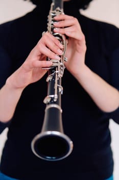 A talented brunette musician showcases her artistry as she gracefully holds and plays the clarinet against a pristine white background