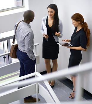 Tablet, communication and teamwork in stairs, talking and corporate employees. Conversation, colleagues or team or coworkers during break, technology or discussion and feedback on workplace stairwell.