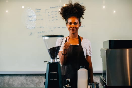 In the coffee shop confident black woman stands at the counter. Portrait of owner a successful businesswoman in uniform smiling with satisfaction providing great service. Inside a small business cafe