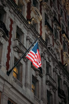 An American flag sways against a backdrop of ornate old-world masonry.