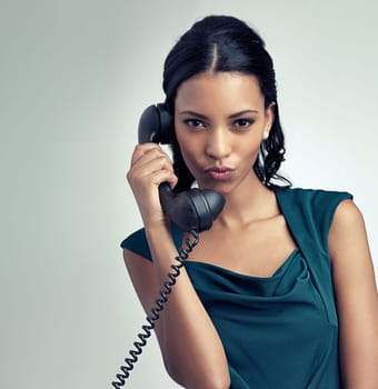 Portrait, receptionist and business woman on telephone with person pouting in studio isolated on a gray background mockup. Face, landline and secretary on call for communication on retro technology.