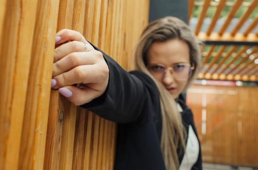 A female person grasping onto a wooden wall with her hands.