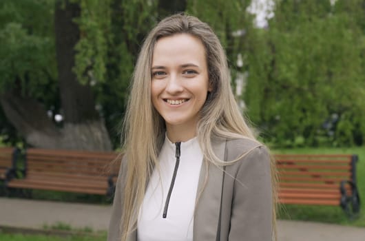 A woman standing next to a park bench in a park setting.