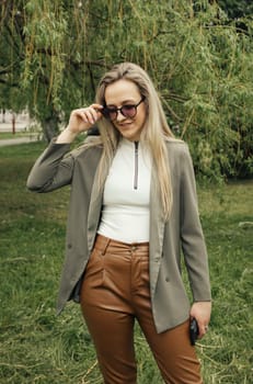 A woman wearing brown pants and a blazer. She stands confidently, showcasing a professional attire in a stylish ensemble.