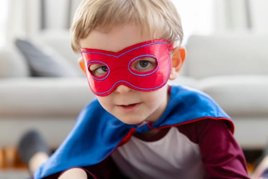 Close-up of a toddler boy dressed in a superhero costume with a mask, portraying strength and playfulness.