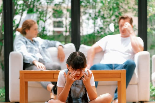 Stressed and unhappy young girl crying and trapped in middle of tension by her parent argument in living room. Unhealthy domestic lifestyle and traumatic childhood develop to depression. Synchronos