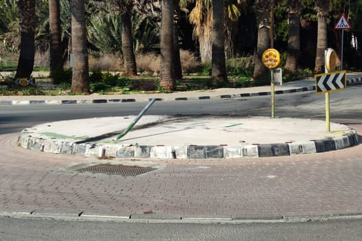 the scene of an accident on a roundabout, a bent road pole and leaked car oil on the asphalt