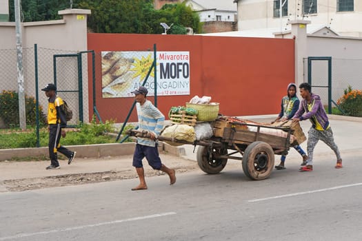 Antananarivo, Madagascar - April 24, 2019: Unknown Malagasy man pulling wooden cart with fruit on main street. There are not many shops in Madagascar, food is usually sold on streets by locals