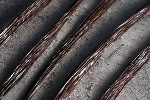 Brown vanilla beans, closeup photo on dark grey stone like kitchen desk