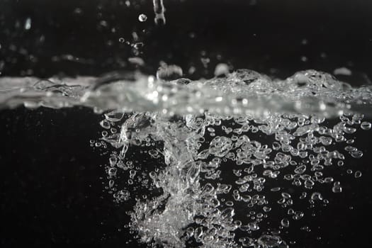 Water splashing as it's poured into aquarium tank, black background