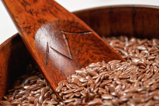 Common flax seeds in small wooden cup with spoon, closeup detail