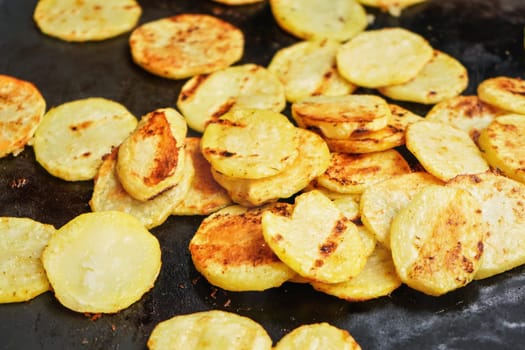 Potatoes cut to round chips grilled on electric grill, closeup detail on slices with brown burn marks