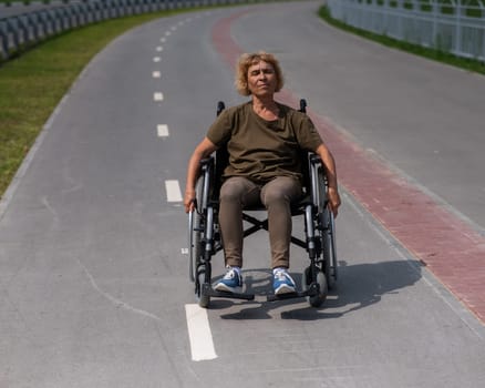 An elderly woman in a wheelchair rides along a bike path