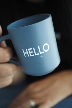 women holding a blue coffee cup with hello word.