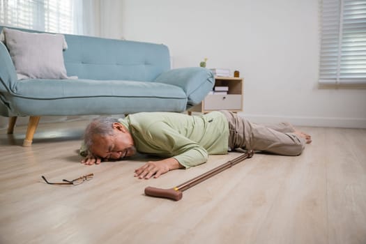 Older senior man headache lying on the floor after falling down he pain and hurt from osteoporosis, Elderly man falling on the floor alone with walking stick at home, Health care and medicine