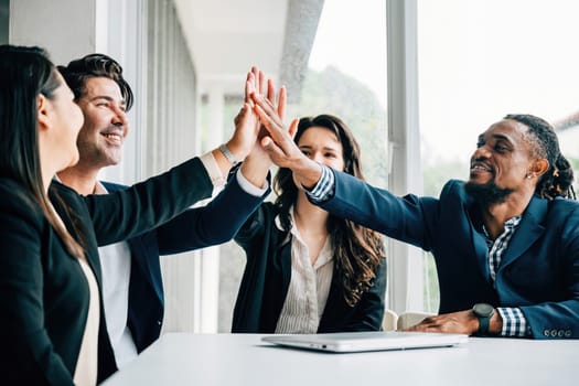 In a corporate setting, an enthusiastic group of business people high-fives during an important meeting, embodying the essence of teamwork and the fulfillment of strategic goals.