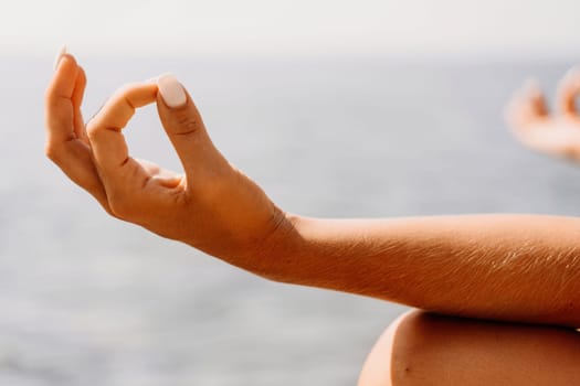 Yoga on the beach. A happy woman meditating in a yoga pose on the beach, surrounded by the ocean and rock mountains, promoting a healthy lifestyle outdoors in nature, and inspiring fitness concept