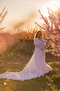 Woman blooming peach orchard. Against the backdrop of a picturesque peach orchard, a woman in a long white dress enjoys a peaceful walk in the park, surrounded by the beauty of nature