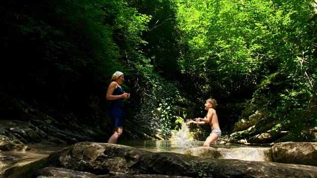 Child playing in forest river on beautiful summer day. Creative. Paradise water reservoir in jungles