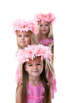 Three beautiful little girls with pink wreaths. Isolated on white