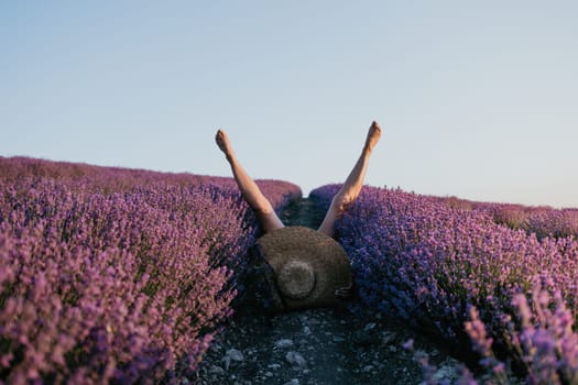 Selective focus. The girls legs stick out of the bushes, warm sunset light. Bushes of lavender purple in blossom, aromatic flowers at lavender fields.