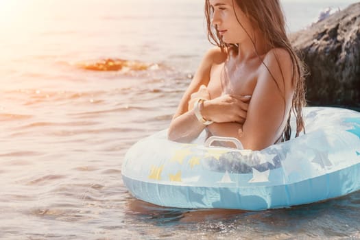 Woman summer sea. Happy woman swimming with inflatable donut on the beach in summer sunny day, surrounded by volcanic mountains. Summer vacation concept