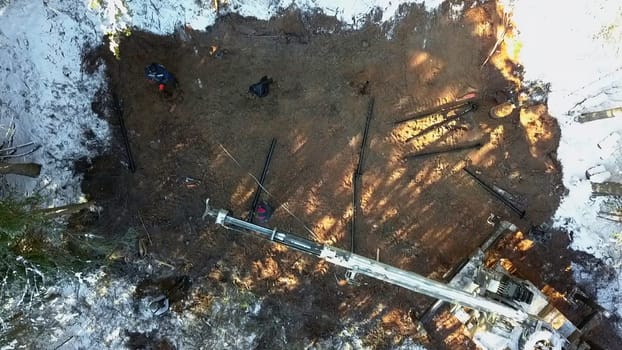 Aerial top view of work on a construction site during winter. Clip. Workers and equipment for works with cold ground