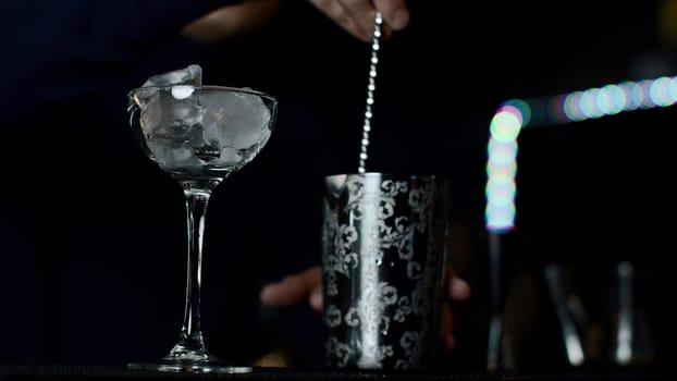 Close up of a bartender is mixing an alcoholic cocktail at the bar or disco club. Media. Process of making an an alcoholic drink