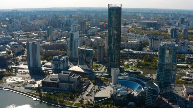 Top view of beautiful city with high-rise buildings in summer. Stock footage. Landscape of modern city from bird's-eye view. Beautiful sunny day in modern city with skyscrapers and river in summer.