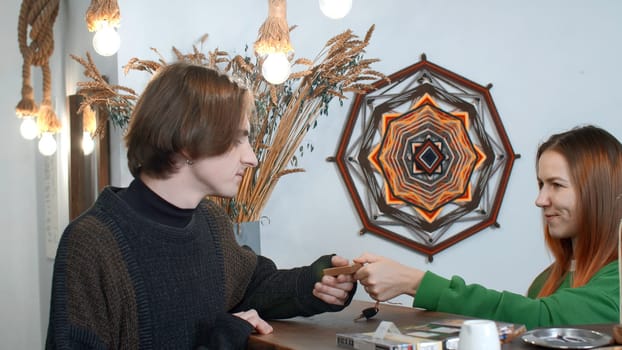 Hotel manager gives the key to the hotel room at the reception. Media. Female receptionist giving old fashioned key to a male visitor at the ethnic interior design hotel