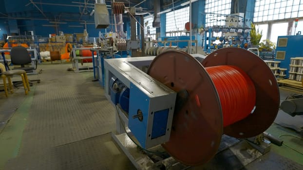 Rotating coil with wires in factory. Creative. Winding cable on to coil on production machine. Process of winding cables at metallurgical plant.