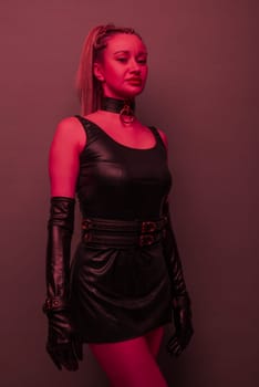 Beautiful young woman in a leather dress and bondage set posing on red light backgound