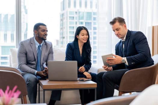 Smart caucasian businessman present marketing idea by using tablet. Group of business team listening while deciding to invest in start up project at modern lounge. Ornamented.