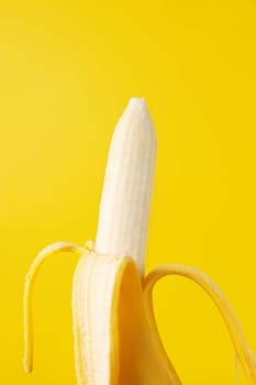 Peeled banana isolated on yellow background.