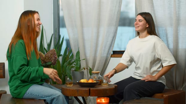 Young women drink tea and have fun chatting in cafe. Media. Young students are having fun talking in cozy college cafe. Women drink tea and laugh in cafe.