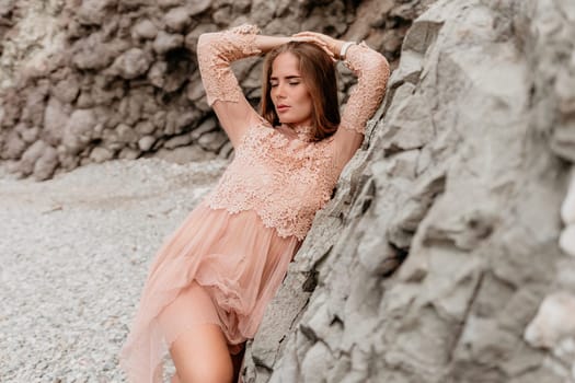 Woman travel sea. Young Happy woman in a long red dress posing on a beach near the sea on background of volcanic rocks, like in Iceland, sharing travel adventure journey