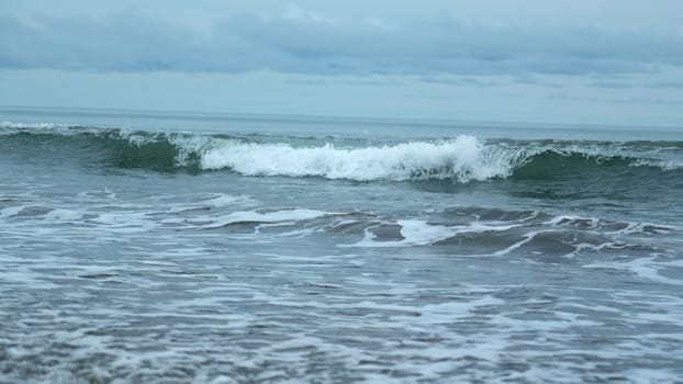 Seascape of beautiful waves on cloudy day. Clip. Beautiful coastal waves on background of horizon with cloudy sky. Coastal waves of North Sea on cloudy day.