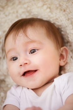 Happy, sweet and closeup of baby on blanket playing for child development and curious face. Smile, cute and young girl kid, infant or newborn relaxing and laying on bed in nursery room at home