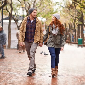 Couple, walk and smile with holding hands at park in cold weather or winter, together and support in London. Relationship, commitment and bonding for romance with soulmate, care and happiness.