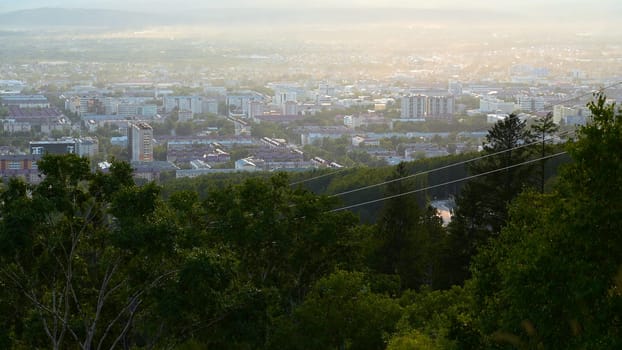 Beautiful view of cable car with view of town in summer. Clip. Green forest on slope with moving cable ways on edge of town. Beautiful city in valley with cable car on sunny summer day.