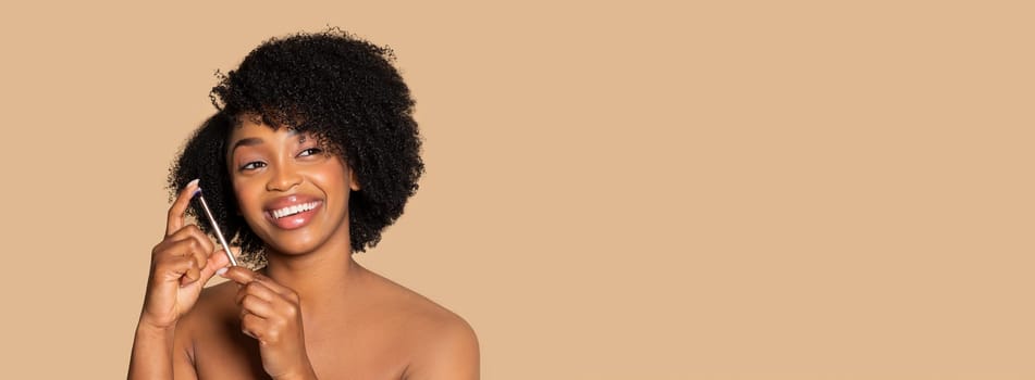 Gleeful black woman showcasing her flawless complexion and curly hair, evoking beauty and happiness on beige tone, free space, panorama