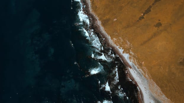 Autumn sunny day on the shore with smooth sea waves. Clip. Aerial view of hills covered by withered grass and dark blue sea