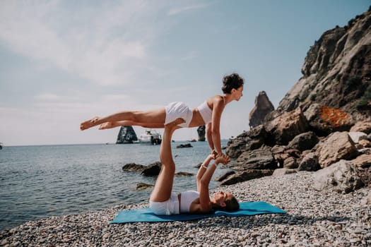 Woman sea yoga. Back view of free calm happy satisfied woman with long hair standing on top rock with yoga position against of sky by the sea. Healthy lifestyle outdoors in nature, fitness concept.