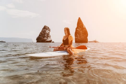 Close up shot of beautiful young caucasian woman with black hair and freckles looking at camera and smiling. Cute woman portrait in a pink bikini posing on a volcanic rock high above the sea