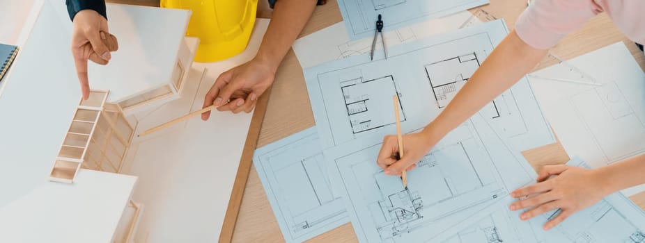 Skilled architect engineer team and interior designer meeting presents house construction on table with blueprint and architectural equipment.scatter around. Focus on hand. Top view. Burgeoning.