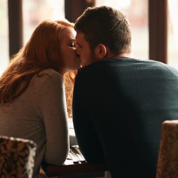 Couple, love and kiss on date at cafe for bonding, romance or healthy relationship with rear view. Man, woman and affection at restaurant with caring, trust and fine dining on anniversary vacation.