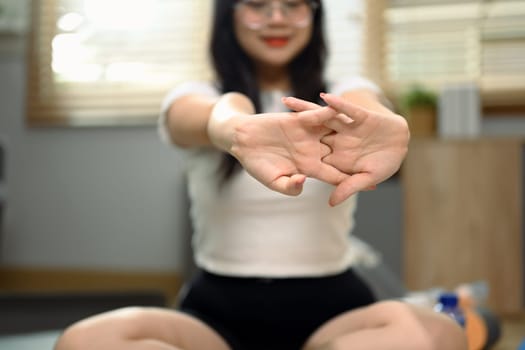 Cropped shot of young woman exercising on mat and stretching arms at home. Healthy lifestyle concept.